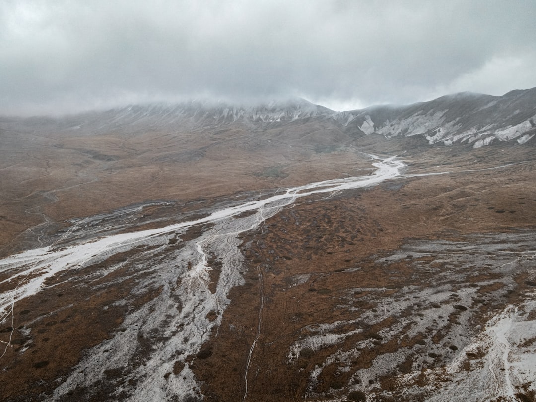 brown and white mountains under white clouds during daytime