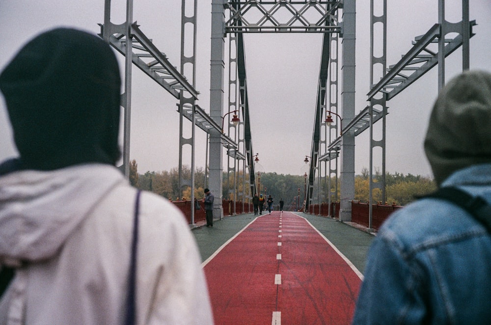 man in white dress shirt standing on red and white bridge during daytime