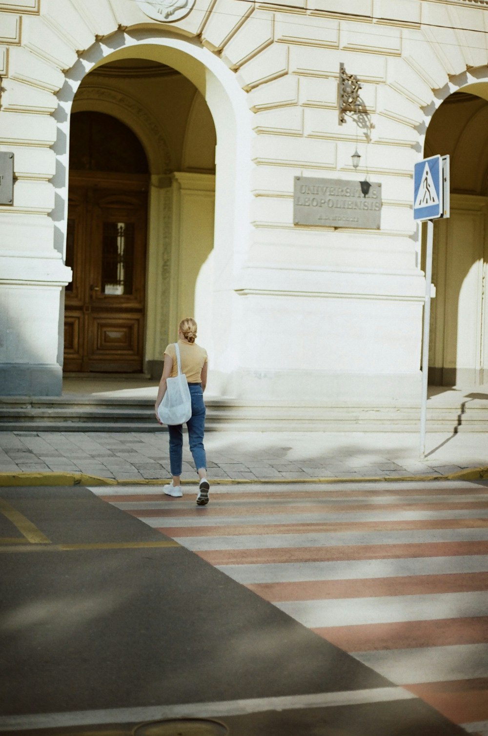 woman in blue denim jacket walking on pedestrian lane during daytime