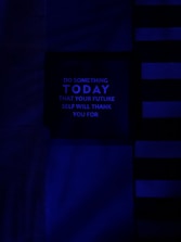 A dark, minimalist image with a motivational message in the center panel. The background features horizontal and vertical lines in various shades of blue, creating a modern and abstract design. The message reads: 'Do something today that your future self will thank you for' in uppercase letters.