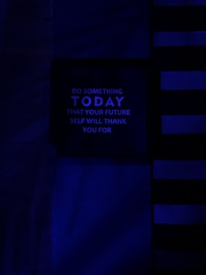 A dark, minimalist image with a motivational message in the center panel. The background features horizontal and vertical lines in various shades of blue, creating a modern and abstract design. The message reads: 'Do something today that your future self will thank you for' in uppercase letters.