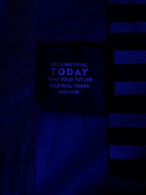 A dark, minimalist image with a motivational message in the center panel. The background features horizontal and vertical lines in various shades of blue, creating a modern and abstract design. The message reads: 'Do something today that your future self will thank you for' in uppercase letters.