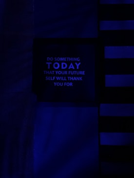 A dark, minimalist image with a motivational message in the center panel. The background features horizontal and vertical lines in various shades of blue, creating a modern and abstract design. The message reads: 'Do something today that your future self will thank you for' in uppercase letters.