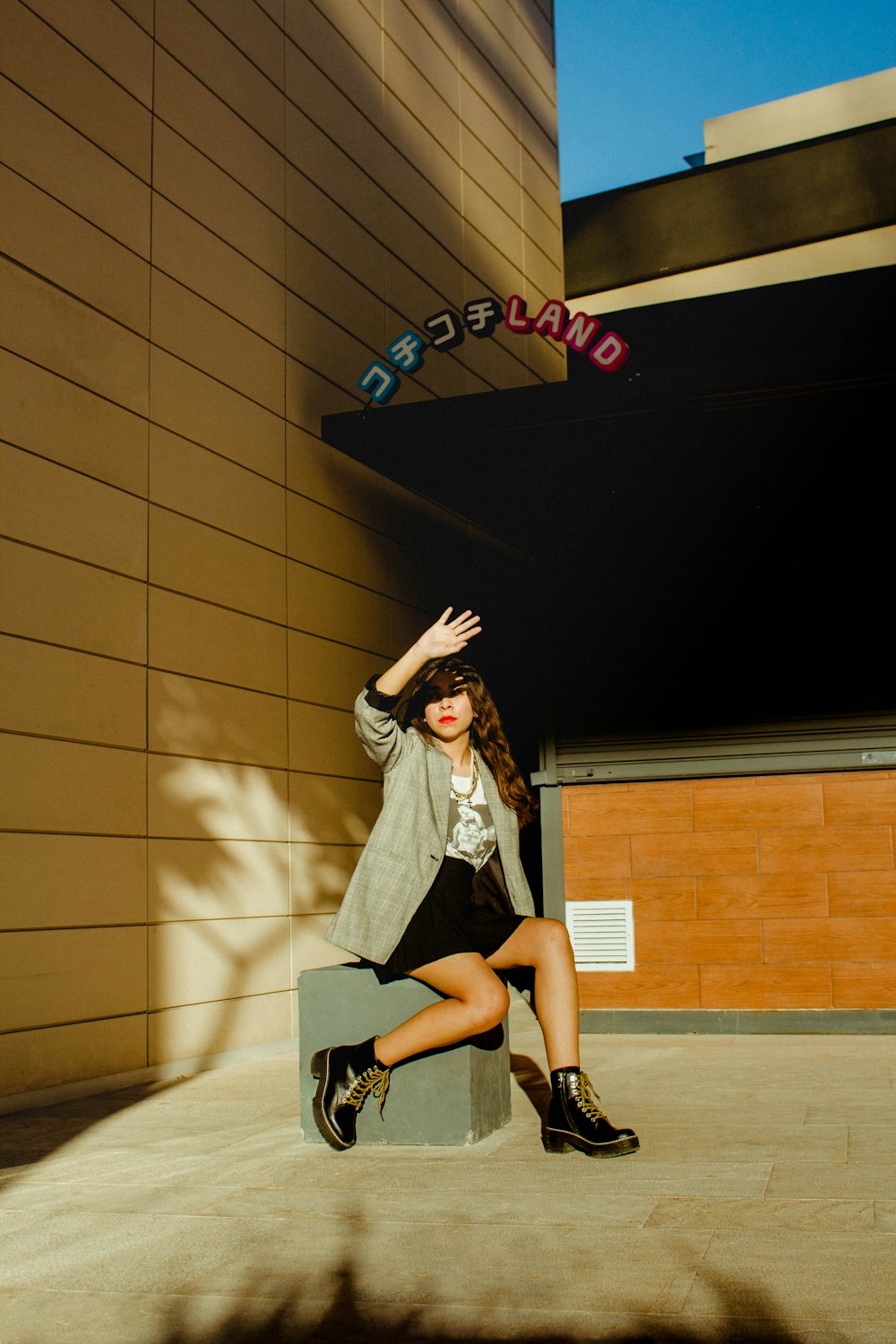 woman in white long sleeve shirt and black skirt standing beside brown wall