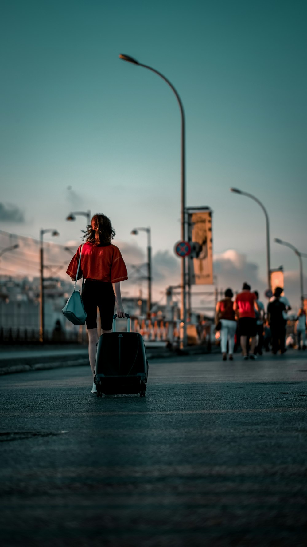 woman in red long sleeve shirt and blue denim jeans carrying black leather bag walking on on on on on