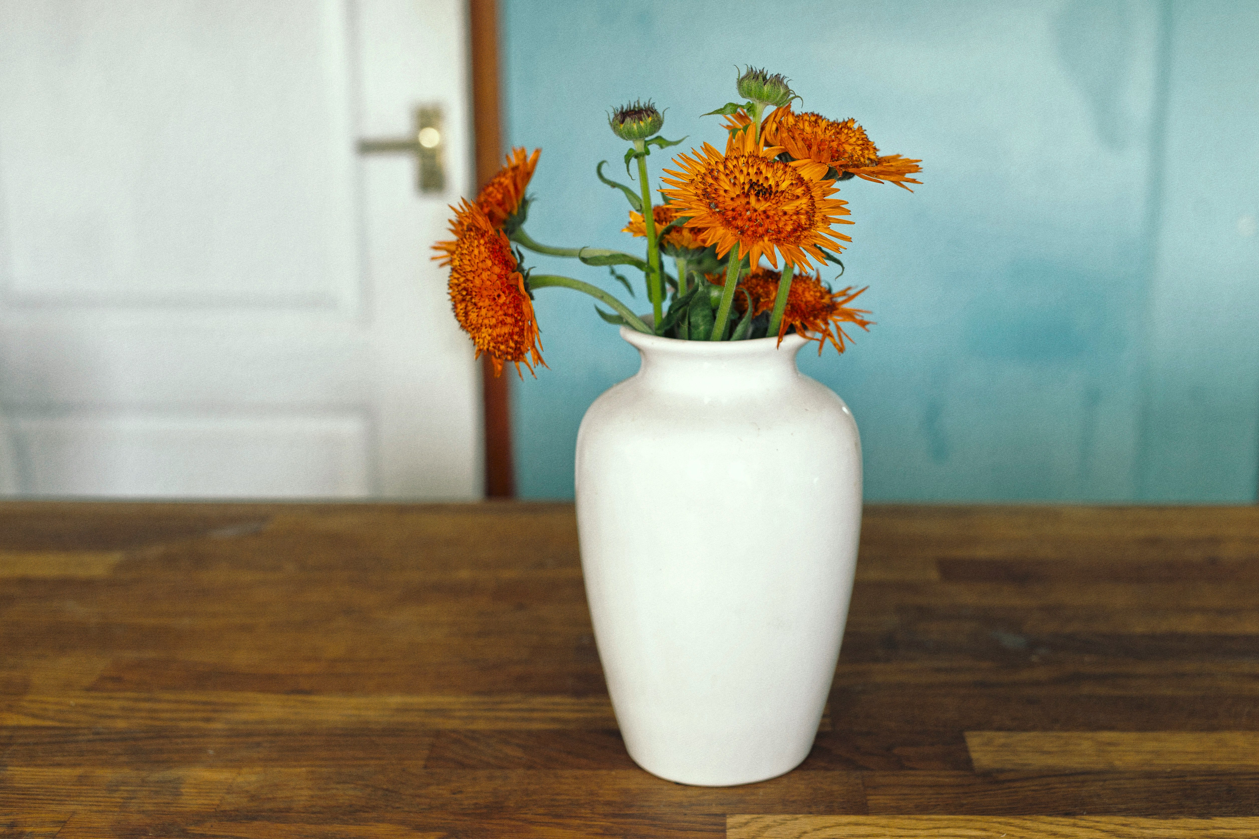 orange and yellow flowers in white ceramic vase
