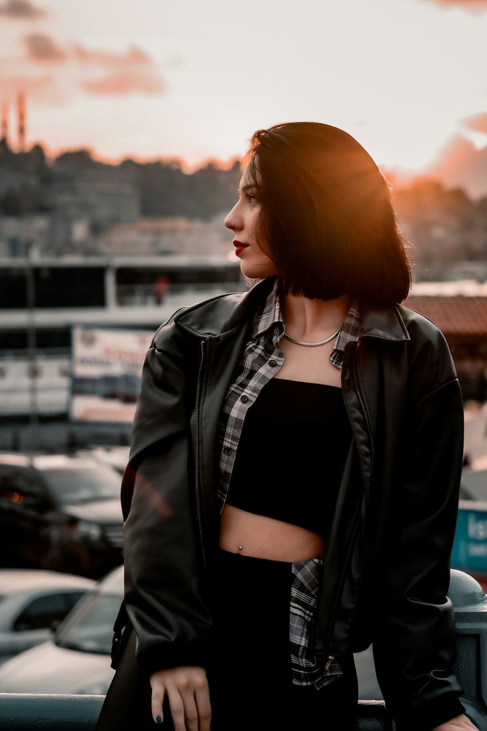 woman in black leather jacket standing near cars during daytime