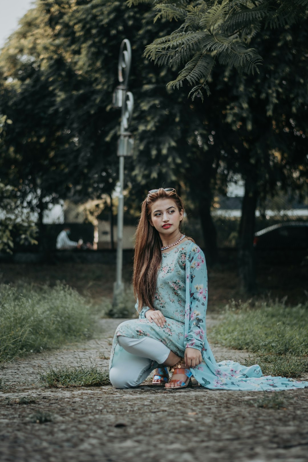 woman in blue and white floral long sleeve dress sitting on green grass field during daytime