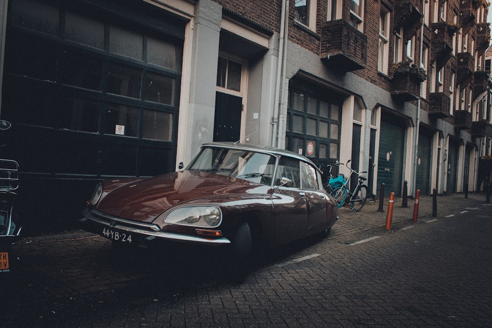 red classic car parked beside building during daytime