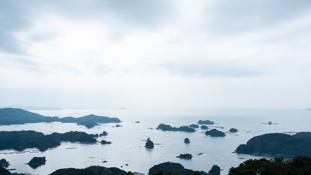 black rocks on body of water under white sky during daytime