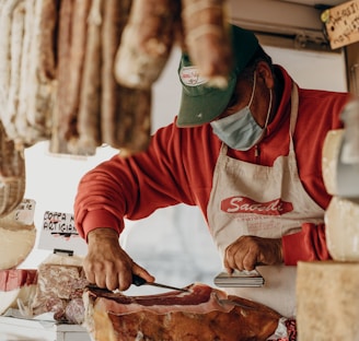 person in red and white long sleeve shirt slicing meat