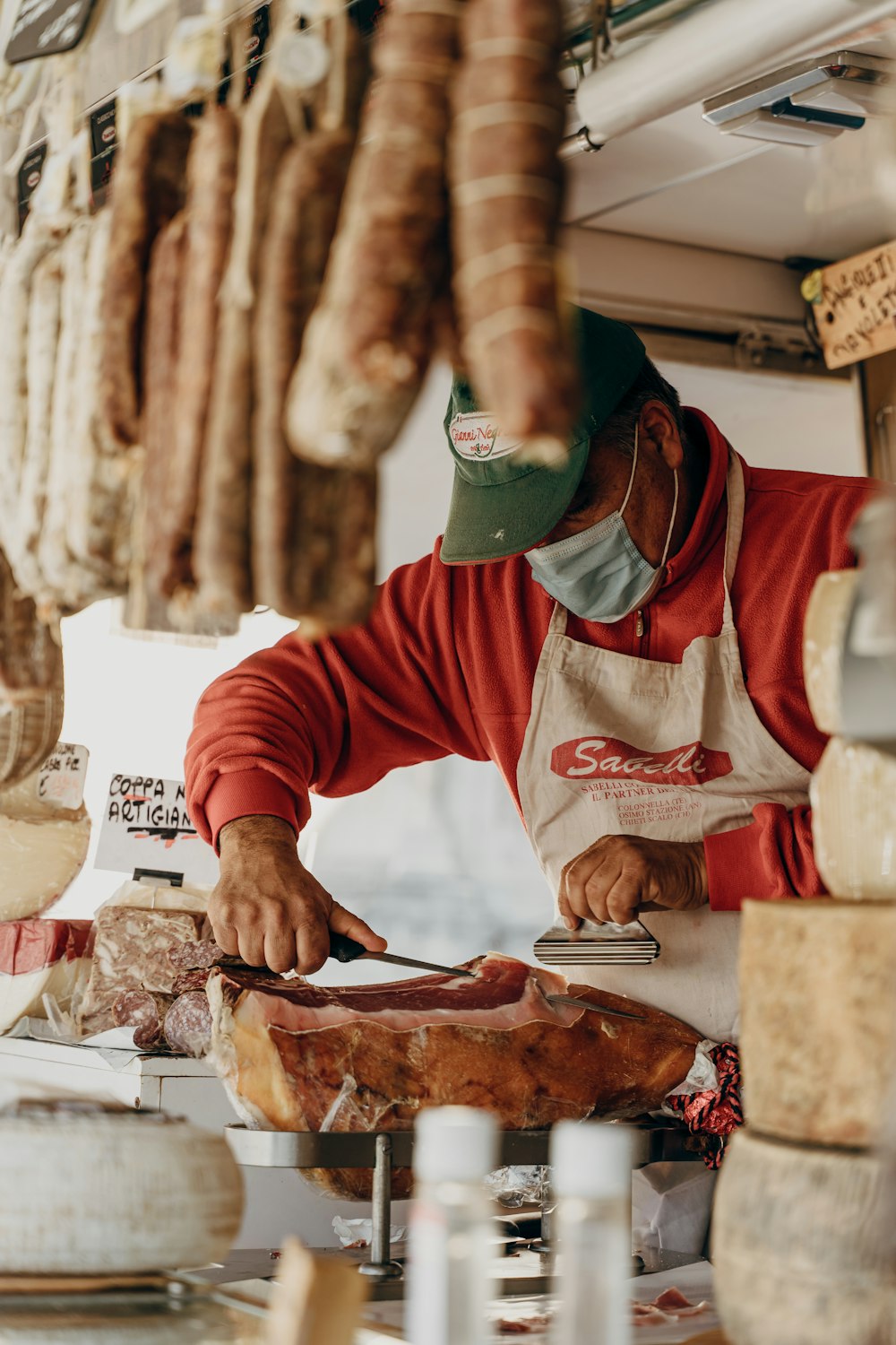 person in red and white long sleeve shirt slicing meat