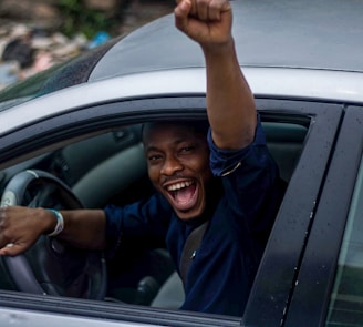 man in black t-shirt and blue denim jeans sitting on car seat