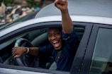 man in black t-shirt and blue denim jeans sitting on car seat