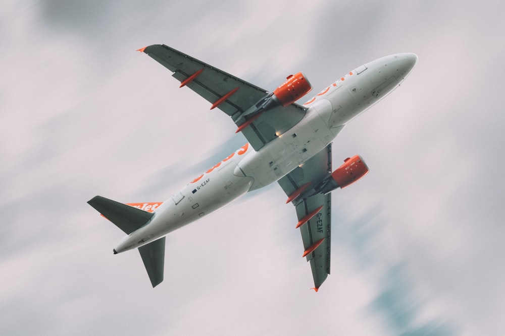 white and red airplane under white clouds during daytime