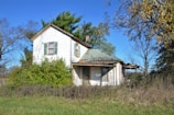 An old, abandoned house with peeling paint and broken windows under a stormy sky.