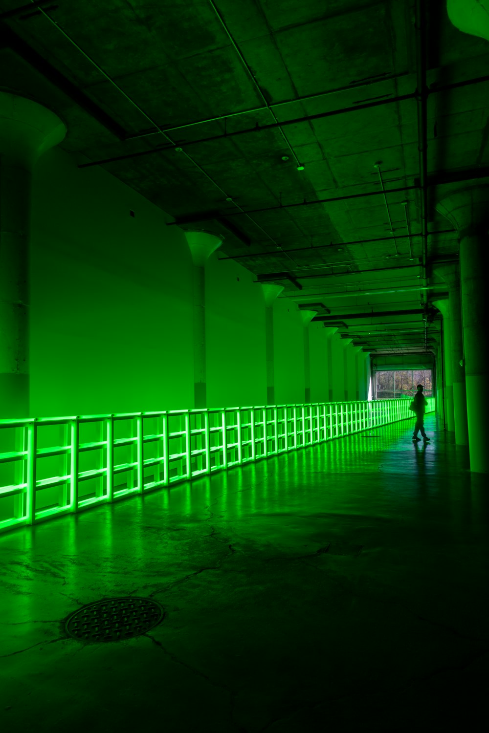 Hombre con chaqueta negra caminando por el pasillo verde