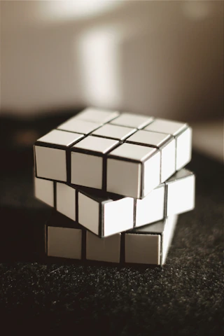 A sleek black and gold 3D printed cube resting on a reflective surface, illuminated by soft futuristic lighting.