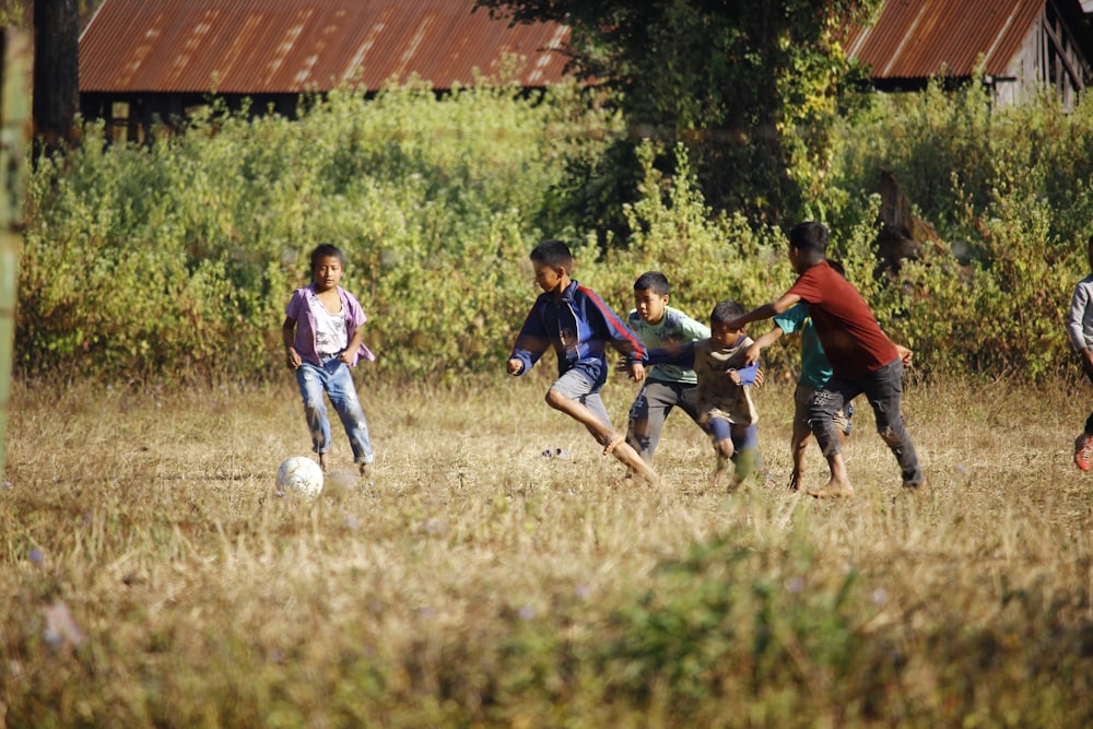 group of people playing soccer on green grass field during daytime