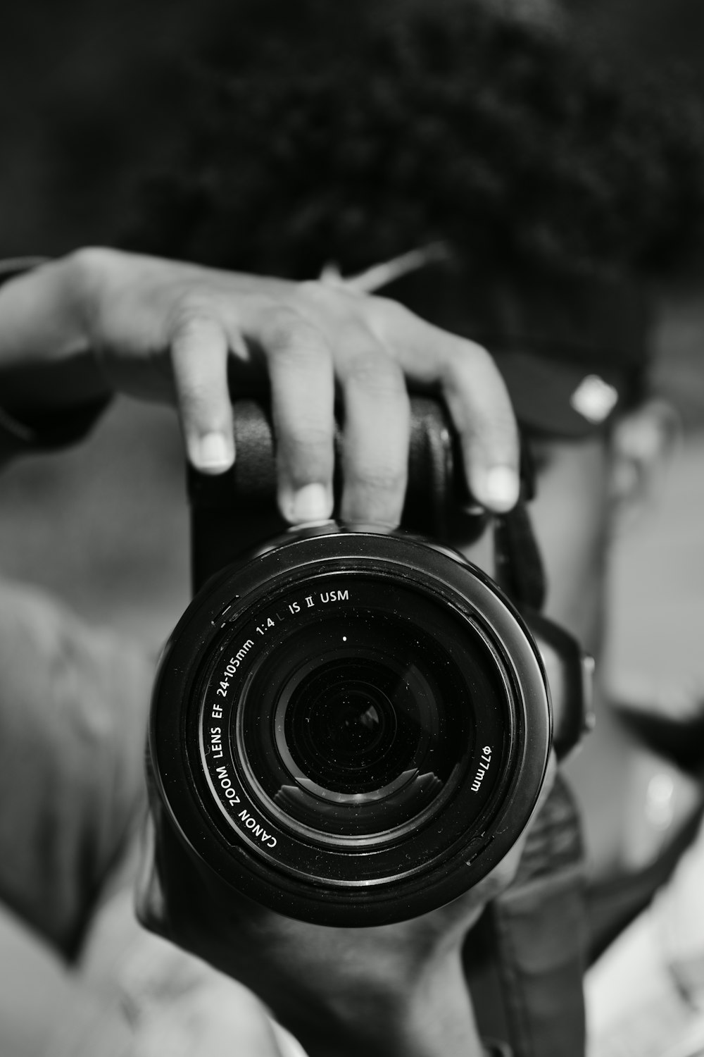 grayscale photo of person holding camera lens