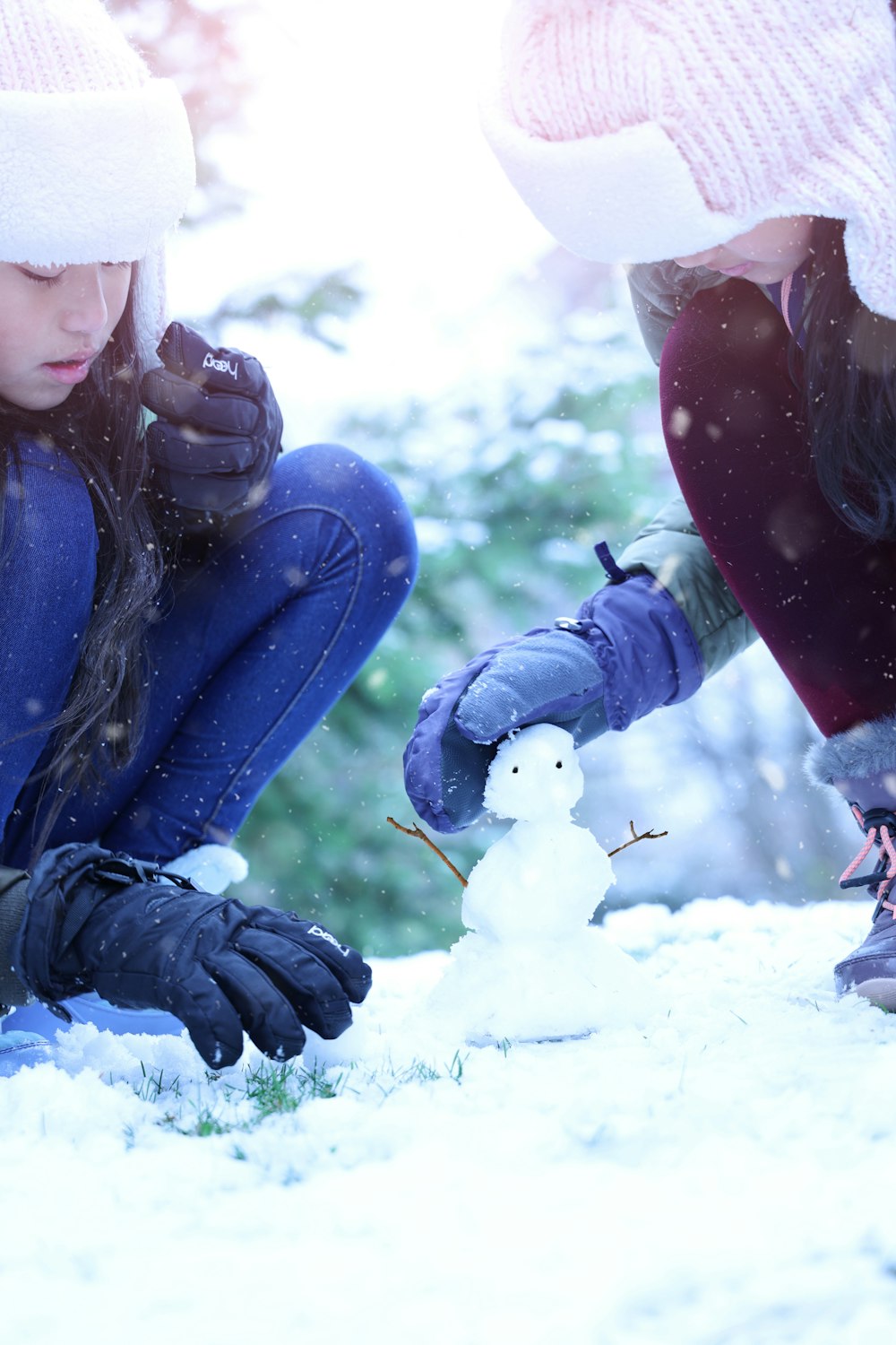 Mujer con chaqueta azul y gorra de punto blanca sentada en un suelo cubierto de nieve durante el día