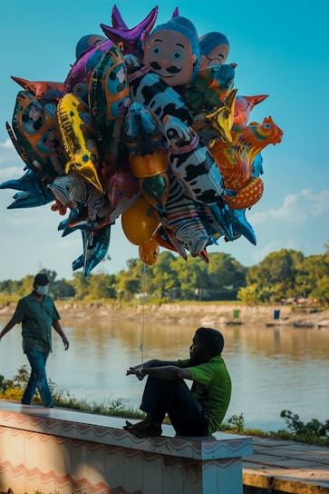 people walking on body of water with dragon balloons during daytime