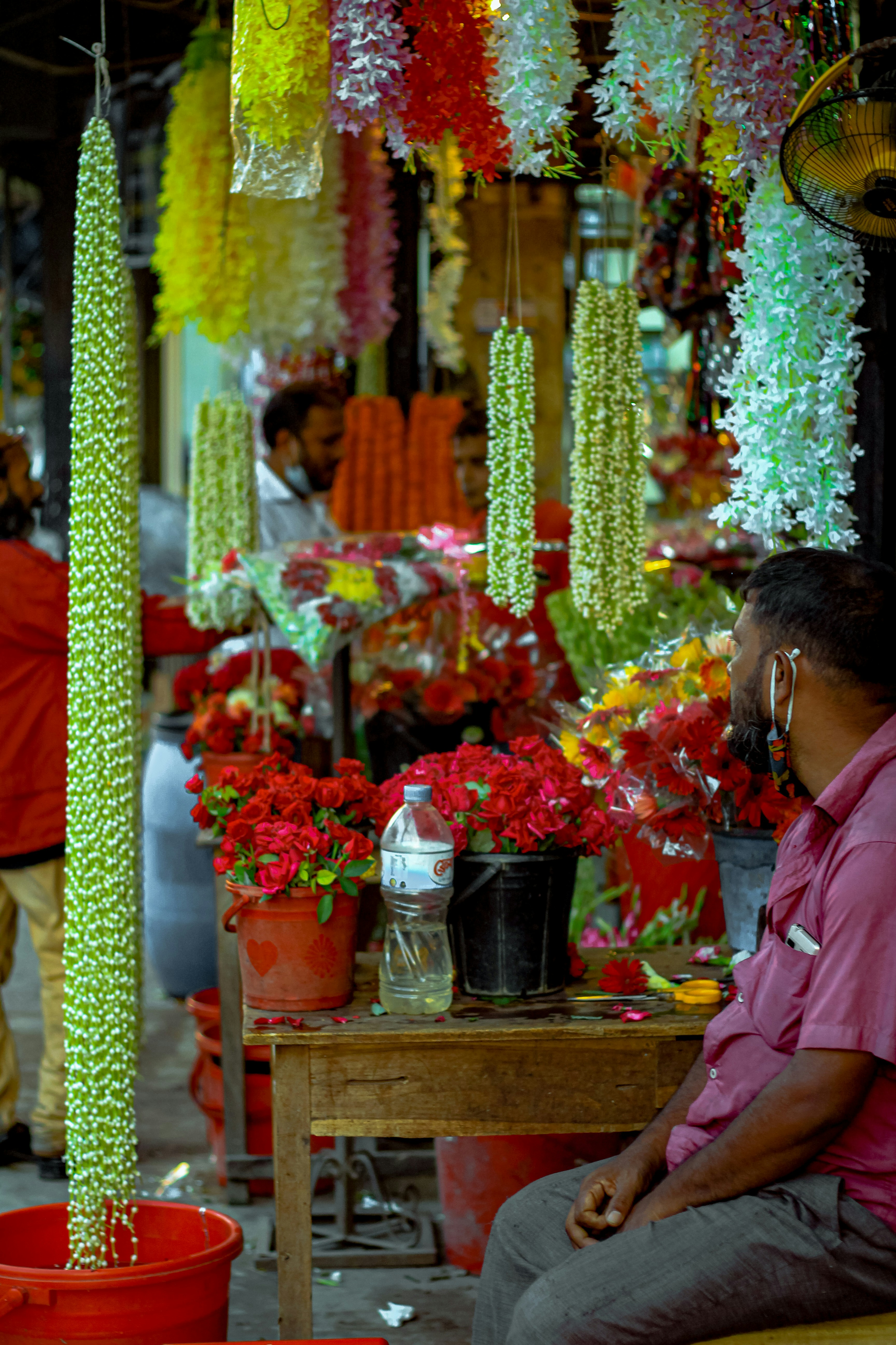 woman in pink and white floral shirt standing near fruit stand