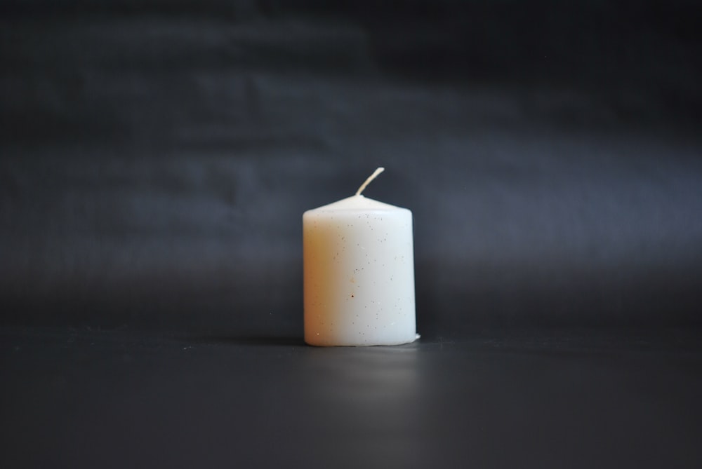 white pillar candle on black surface