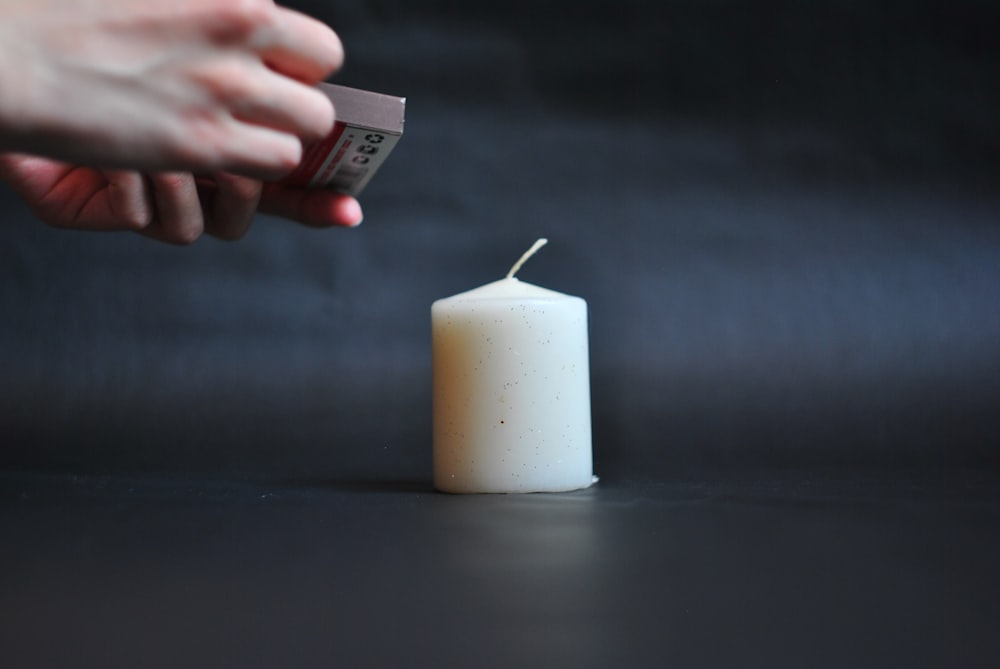 white pillar candle on black table