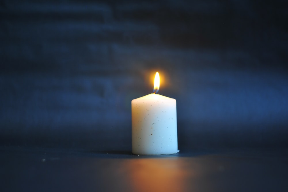 white pillar candle on black surface