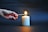 Close-up of a hand lighting a scented candle with a matchstick.