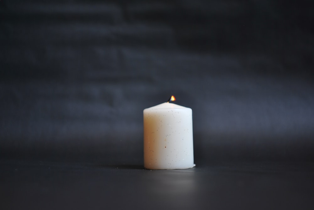 white pillar candle on black surface