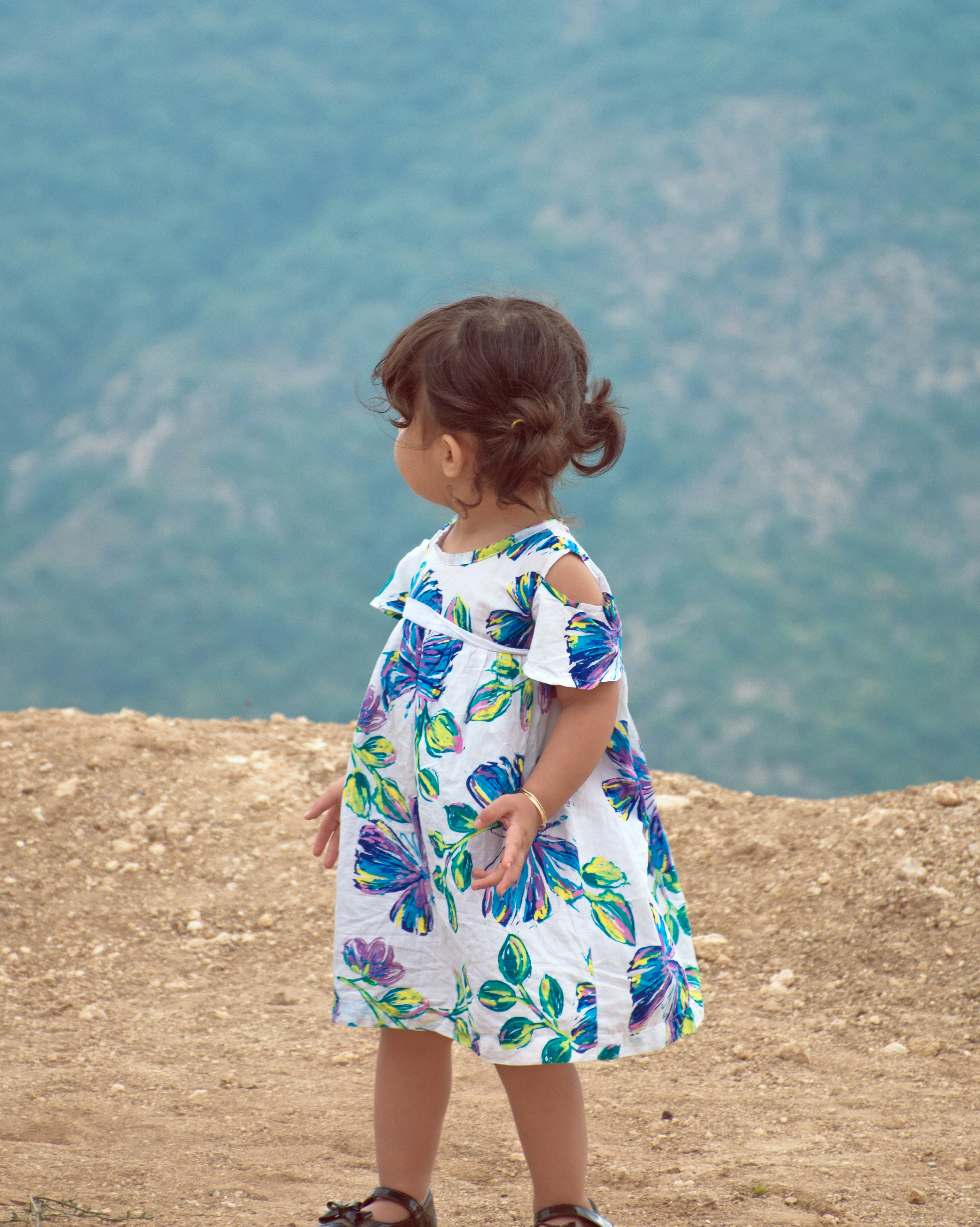 girl in blue and white floral dress standing on brown sand during daytime