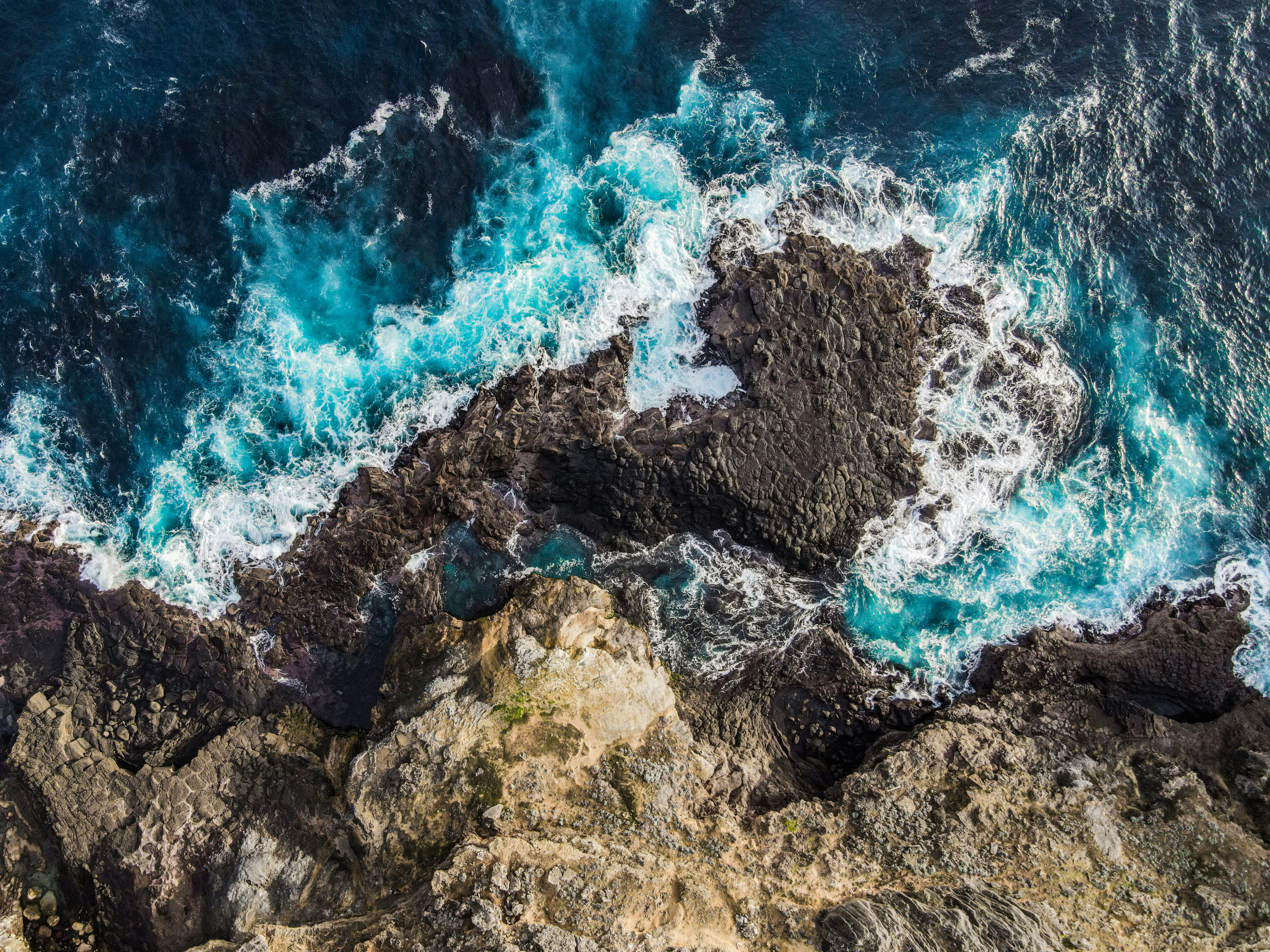 brown and black rock formation beside body of water