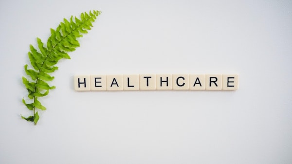 Mot "healthcare" écrit avec des lettres de Scrabble à côté d'une feuille de fougère placée à sur la gauche