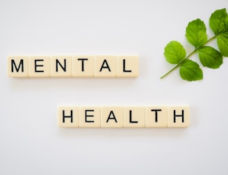 the word mental health spelled with scrabbles next to a green leaf