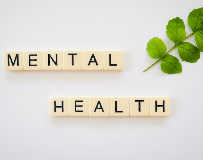 the word mental health spelled with scrabbles next to a green leaf