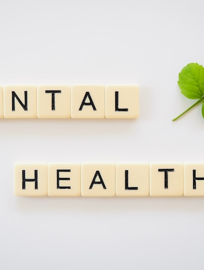 the word mental health spelled with scrabbles next to a green leaf