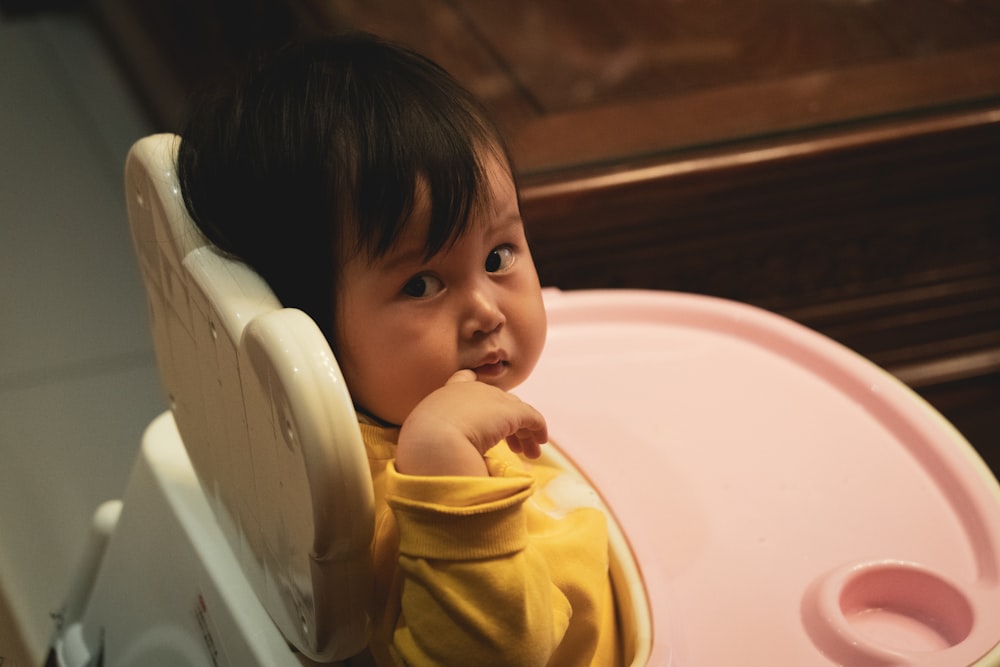 baby in white and pink high chair