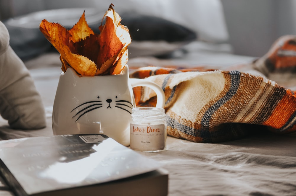 white ceramic mug beside brown and white textile