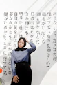 woman in blue long sleeve shirt and black pants sitting on white and black floral textile