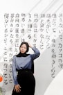 woman in blue long sleeve shirt and black pants sitting on white and black floral textile