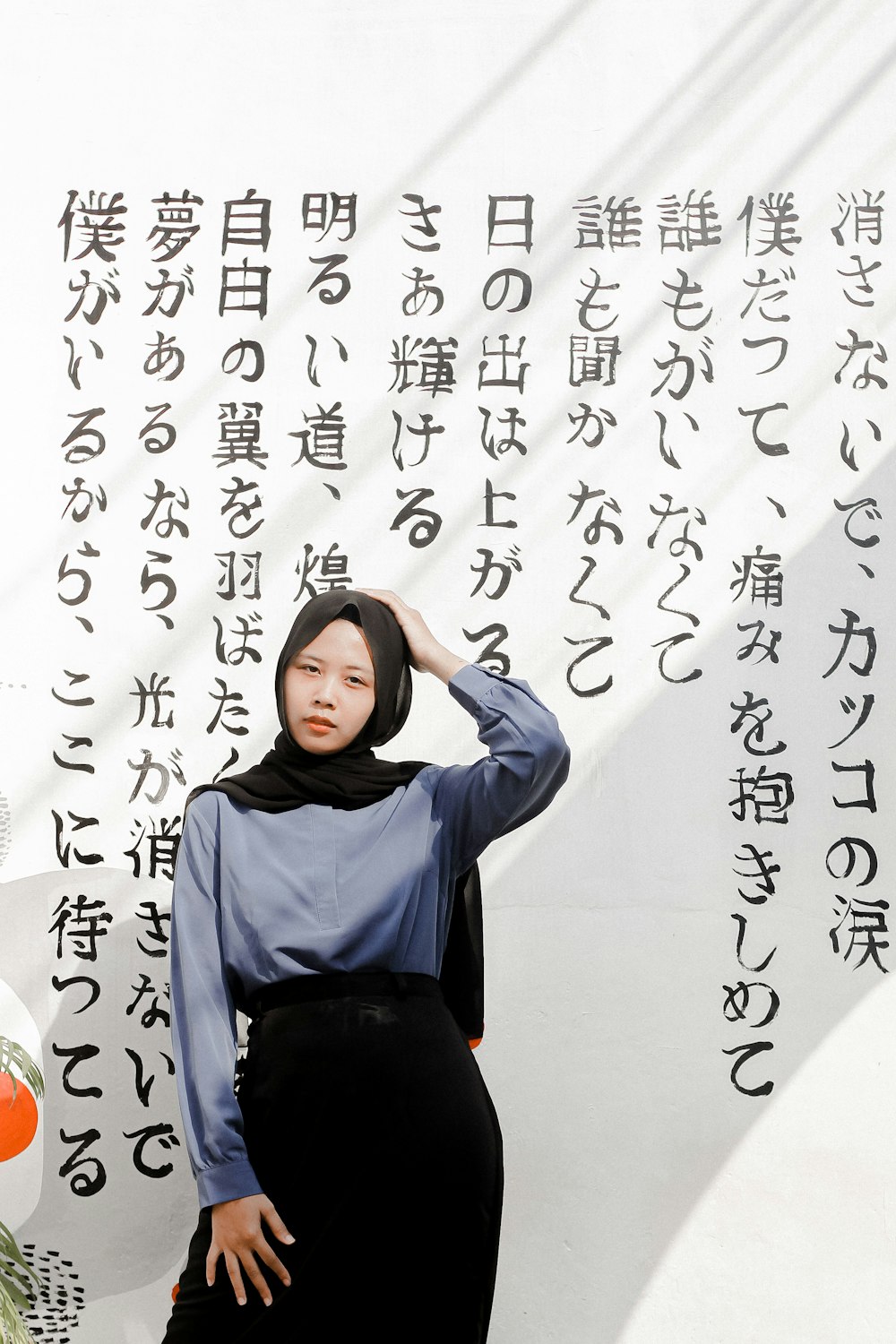 woman in blue long sleeve shirt and black pants sitting on white and black floral textile