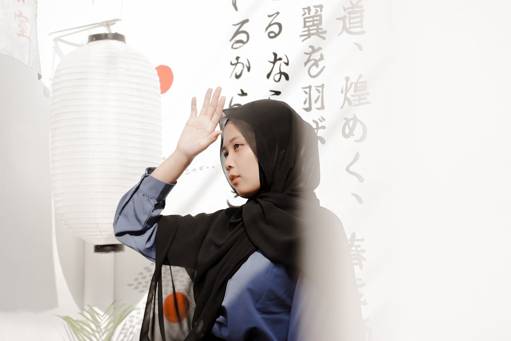 woman in gray hijab standing near white wall