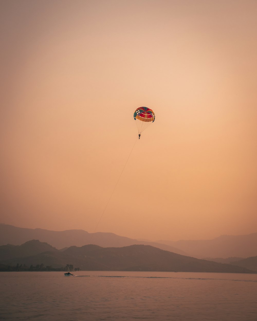 red and white parachute over the mountains during sunset