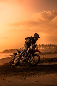 silhouette of man riding motorcycle on beach during sunset
