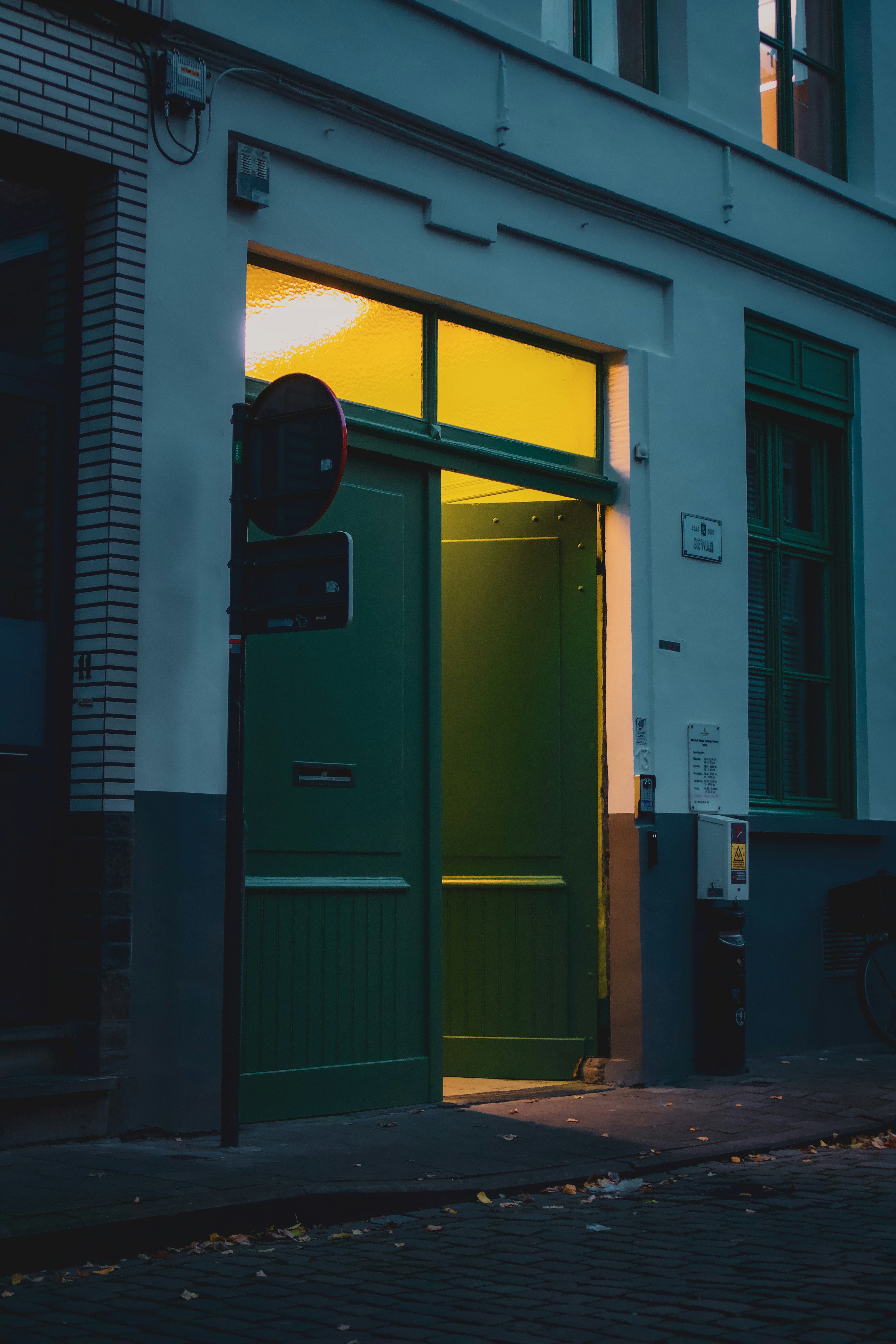 green wooden door beside white concrete building during daytime