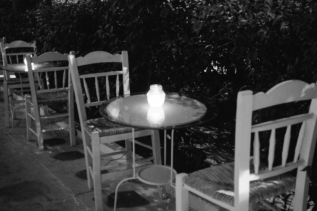 grayscale photo of round table with chairs