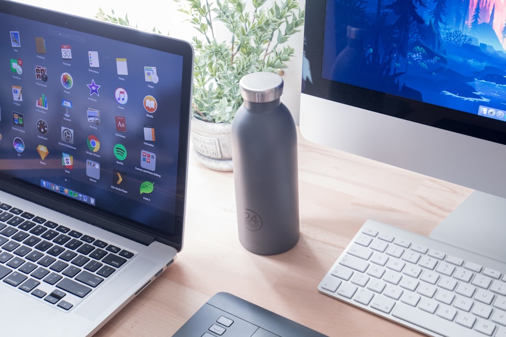 black and silver laptop computer beside white plastic bottle