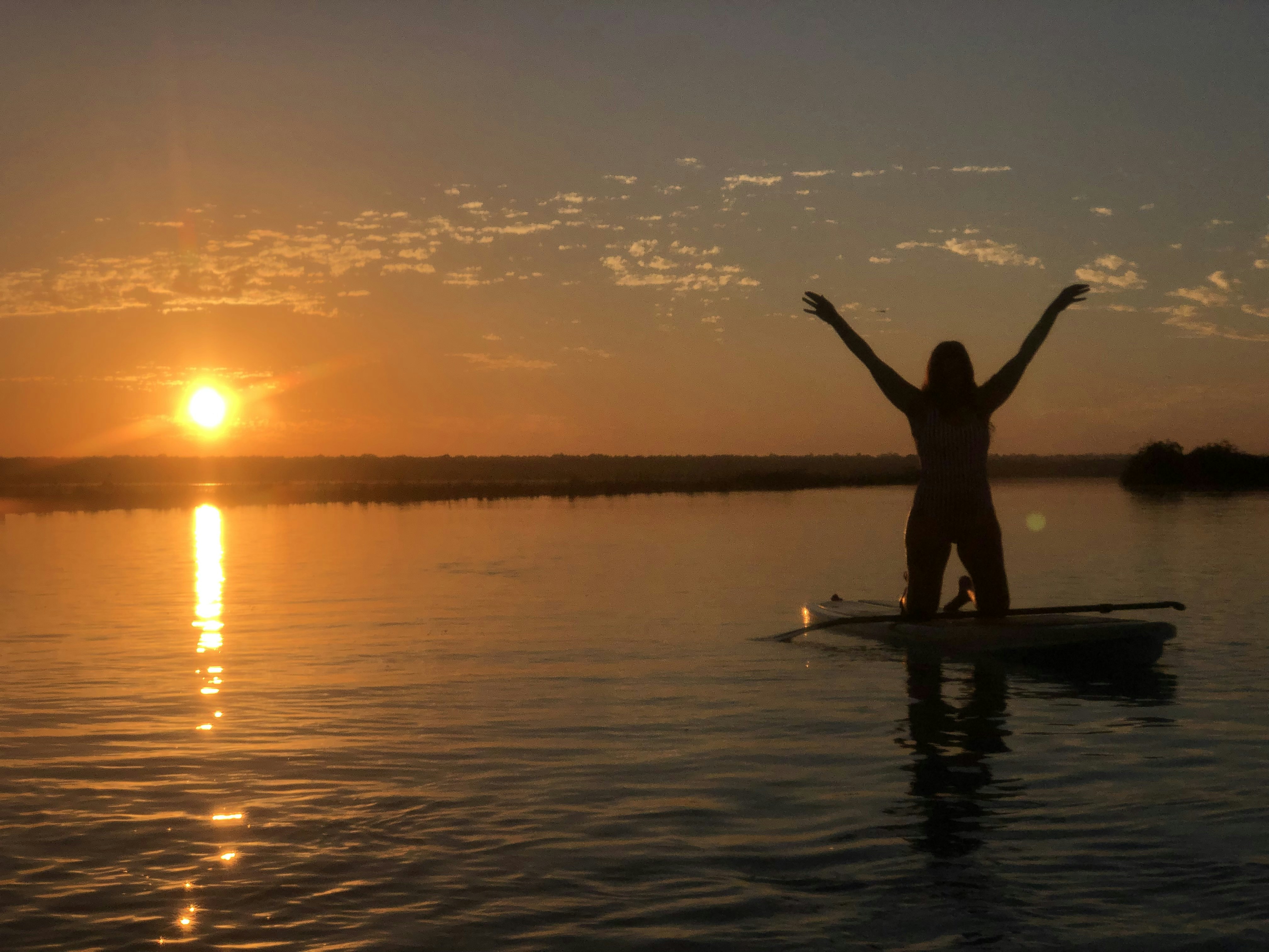 Silueta de mujer de pie sobre el cuerpo de agua durante la puesta del sol